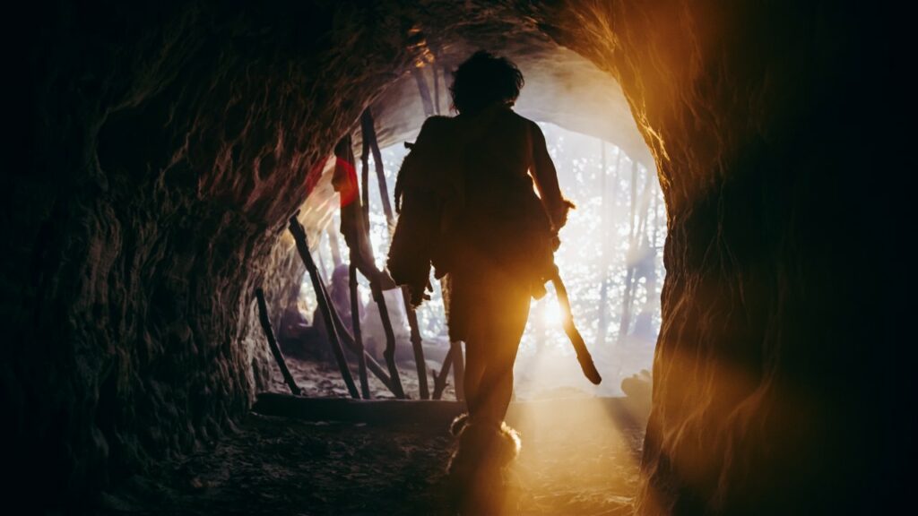 Cave man walking toward the exit of a cave 